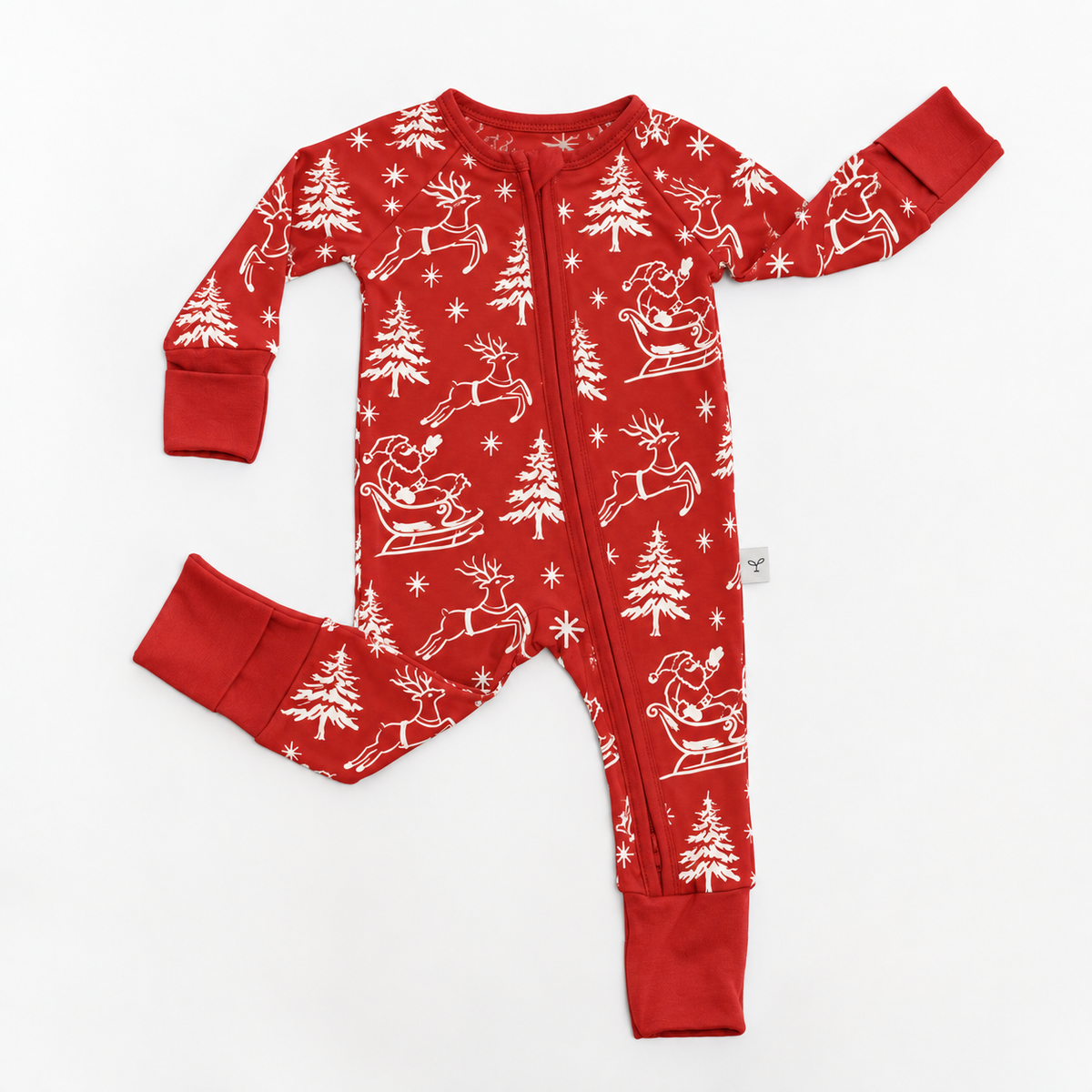 A red long-sleeve baby footed one-piece pajama with a white Christmas print of Santa Claus, reindeer, pine trees, and snowflakes, laid flat on a white background.
