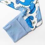 Pattern of blue dinosaurs on white bamboo fabric pajamas with cuff hands.