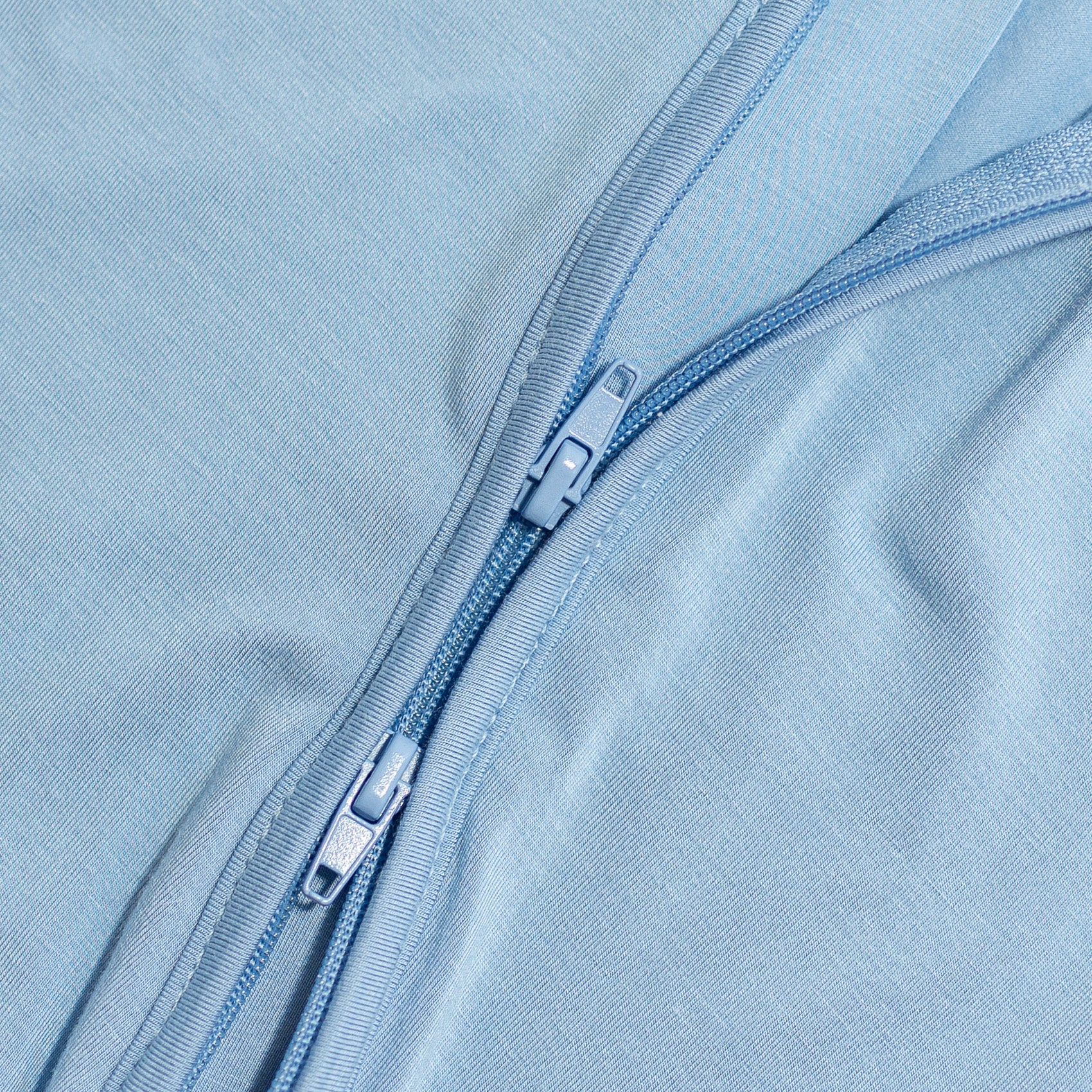 Close-up of a blue zipper on blue bamboo fabric.