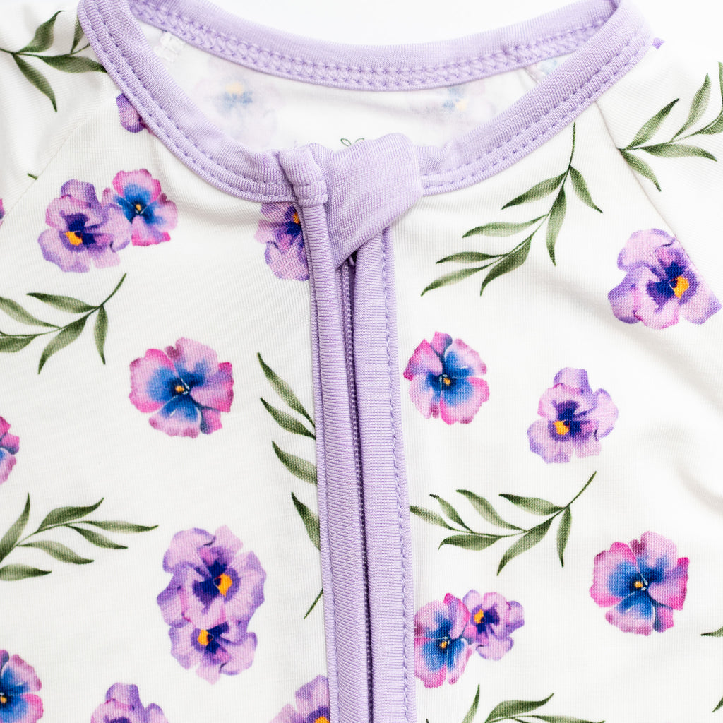 Close-up of a purple zipper on a white background with floral pattern bamboo fabric.