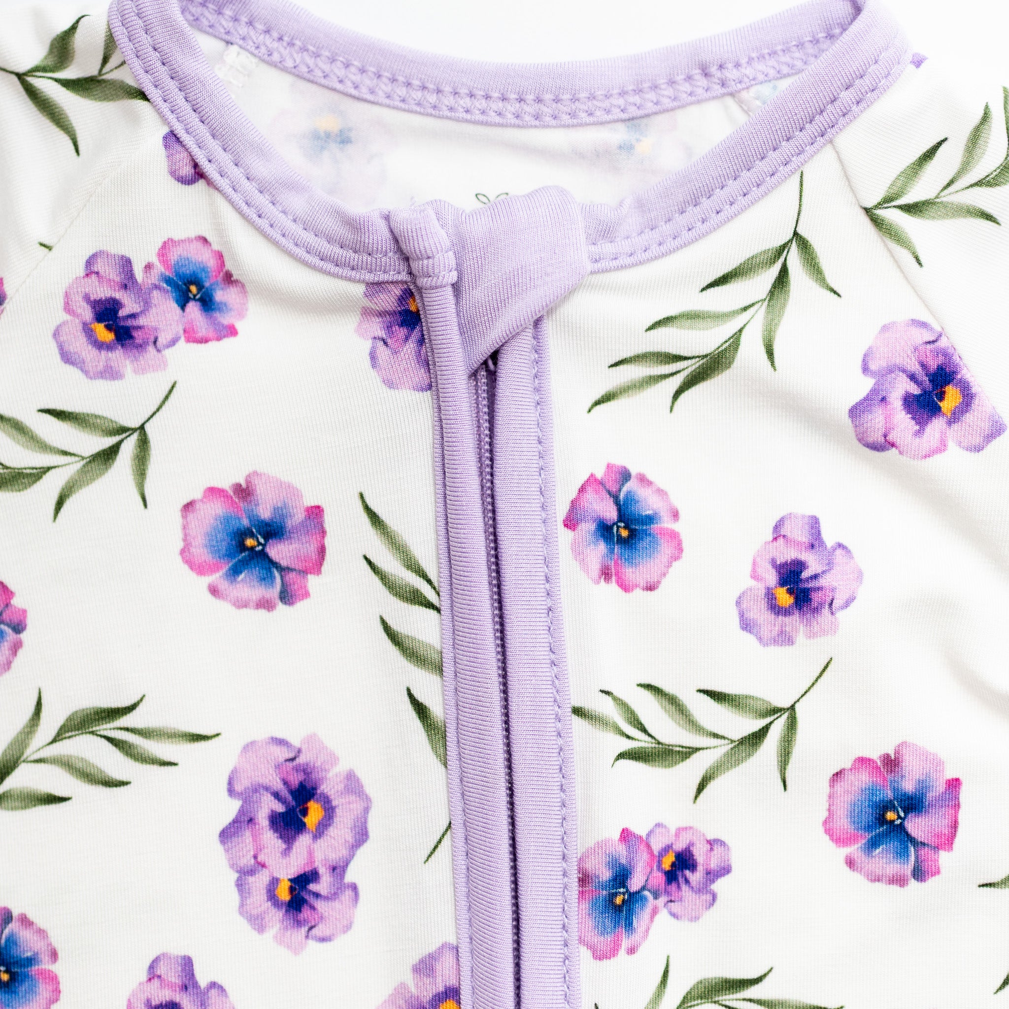 Close-up of a purple zipper on a white background with floral pattern bamboo fabric.